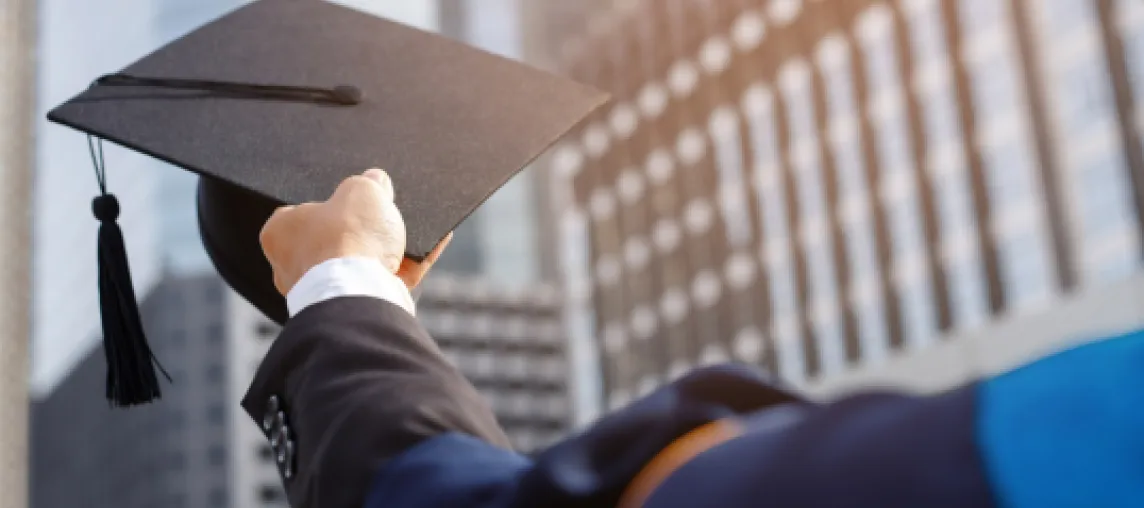 foto con studente di spalle che alza il cappello di laurea